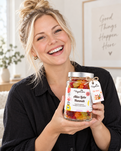 Blonde Frau hält personalisierte Vegablum Bio Gummibärchen 280 g mit Wunschtext Alles Liebe Hannah
